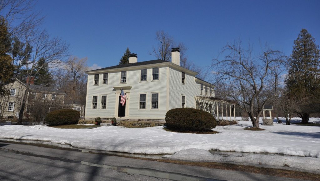 A white two-story colonial house at 8 Lane Road in Derry, New Hampshire, with snow on the lawn