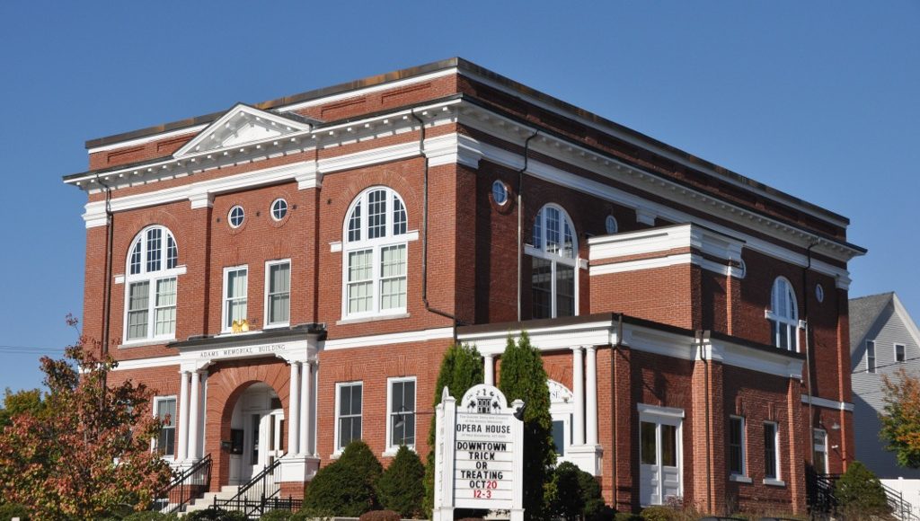 The brick Adams Memorial Building in Derry, New Hampshire, home of the Derry Opera House, with an Opera House sign out front