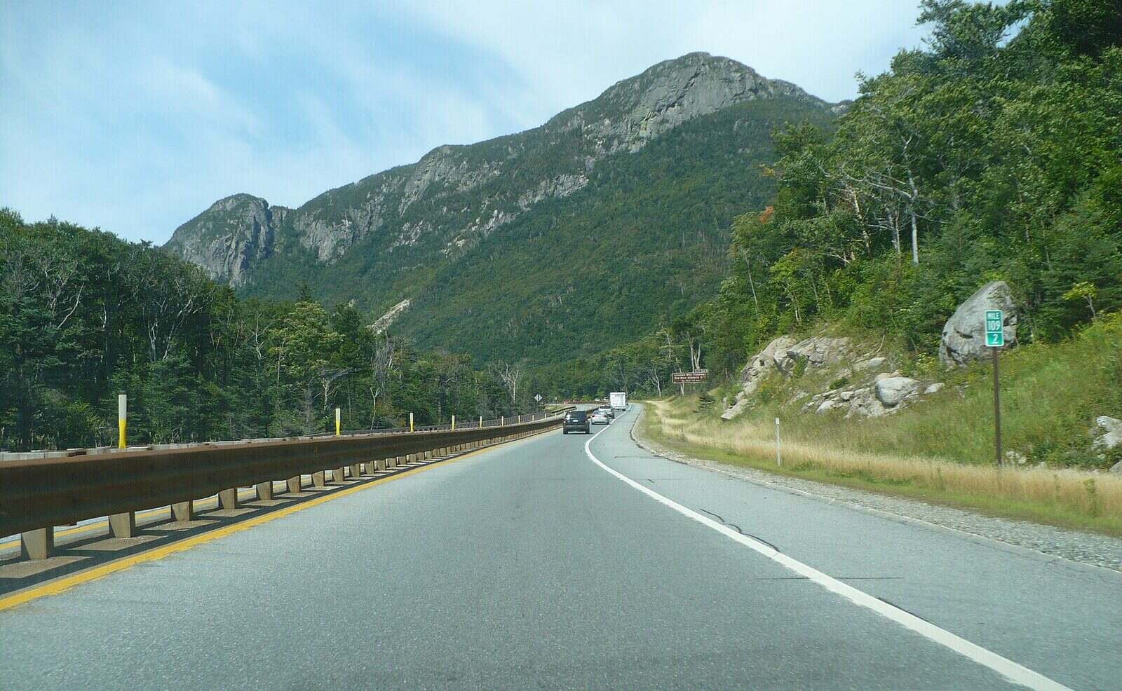 Asphalt parkway through Franconia Notch with mountains and a mile marker
