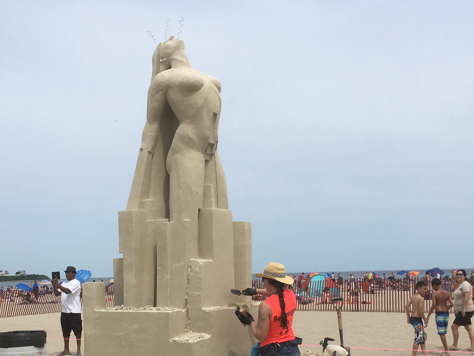 Sculptor working a tall sand figure at the Hampton Beach sand classic